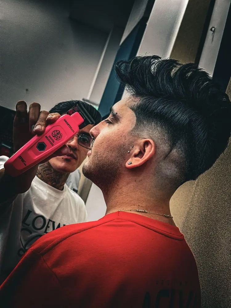 Barbero haciendo un fade con máquina roja